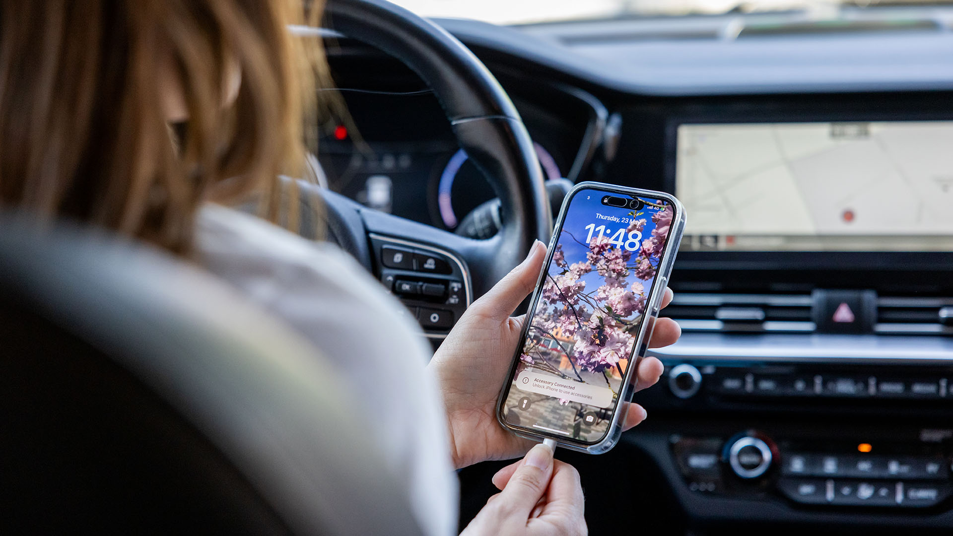 Bilförare håller i sin mobiltelefon.