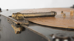 Skivplatta med utstansade spår och en avläsande metallarm.