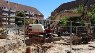 Grävskopa på innergård i bostadsområdet.