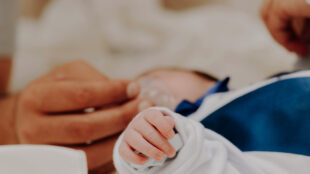 Nyfödd bebis med mamma i sjukhussäng.