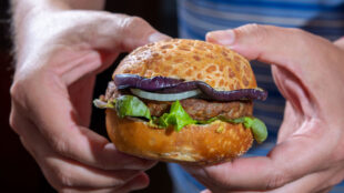 Man håller i en växtbaserad hamburgare.