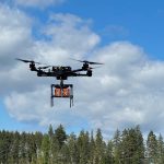 Drönare flyger över skogsområde.