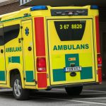 En gul ambulans utanför ett sjukhus.