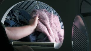 Man håller i en rosa handduk i tvättmaskinen