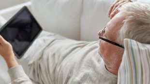 Äldre man vilar sig i soffan